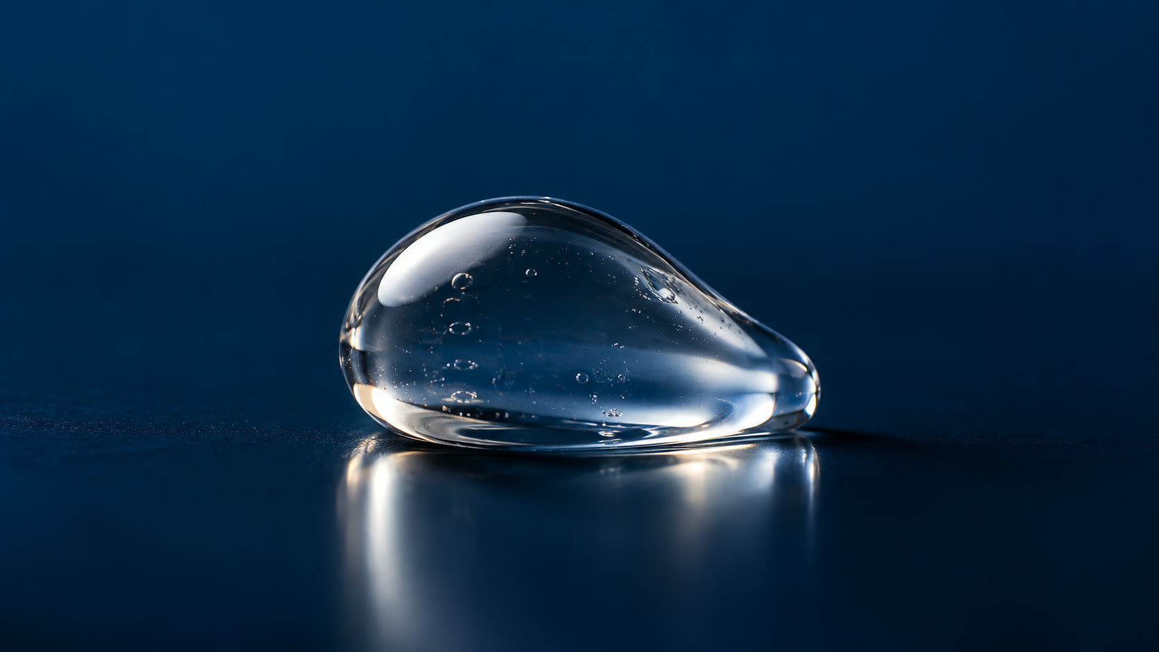 Gota de gel transparente refletindo luz sobre superfície azul